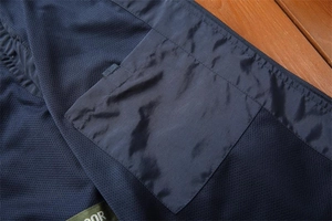 Detail of dark blue outdoor vest featuring breathable mesh lining and a hidden inner pocket