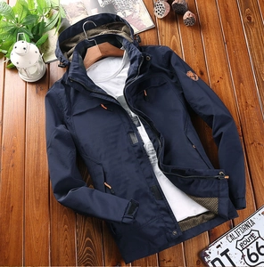 Detail of navy windbreaker showing waterproof fabric and orange zipper on wood background