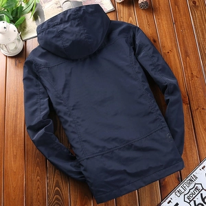Back view of a men's navy blue hooded windbreaker with tactical patch on textured wood