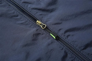 Close-up of navy blue ripstop fabric with bronze metal zipper and neon green details