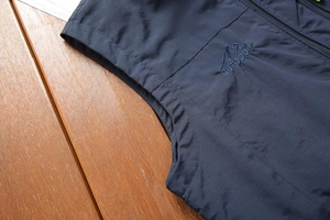 Detail of navy outdoor vest showing mountain embroidery and windproof fabric texture