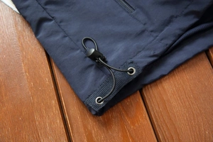 Detail of navy blue vest hem with adjustable elastic drawstring and plastic toggle