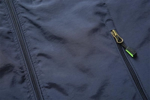 Detail of dark blue outdoor vest featuring ripstop fabric and green zipper accents
