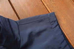 Detailed close-up of double-stitched hem on a navy casual vest with smooth fabric texture