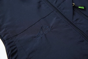 Detail of navy outdoor vest showing mountain embroidery and neon green zipper puller