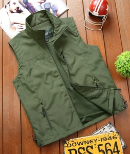 Detail of green outdoor vest with mesh lining, zippers and mountain logo on wood background