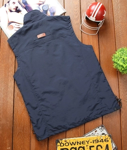 Detail view of navy outdoor vest showing classic leather patch and drawstring hem