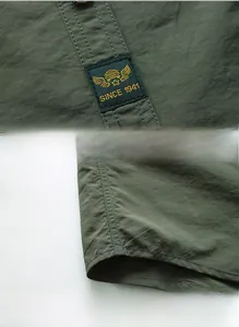 Detail of army green shirt featuring custom woven label and reinforced curved hemline