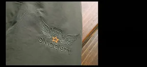 Detail of military green jacket with high-quality embroidery featuring rugged outdoor car theme