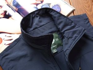 Detail of dark blue stand collar vest with mesh lining and zipper on wooden background