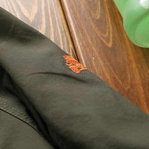 Herren Windbreaker in Olivgrün mit hochwertiger oranger Stickerei am Ärmel für Outdoor