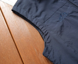 Detail of navy blue outdoor vest featuring embroidered outdoor text and mountain logo