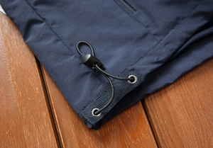Detail view of navy outdoor vest hem with adjustable black elastic drawstring and cord lock