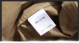 Close-up detail of the 100% cotton fabric care label on a khaki casual military shirt