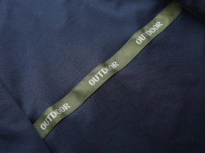 Detail of breathable navy mesh fabric with green 'OUTDOOR' strap and premium stitching