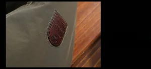 Dettaglio della giacca outdoor verde militare con toppa logo in pelle marrone goffrata