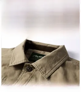 Detailed close-up of khaki outdoor jacket collar featuring metal button and brand woven label