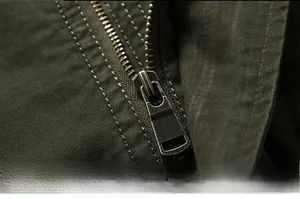 Macro detail of military green jacket featuring a heavy-duty bronze metal zipper and stitching