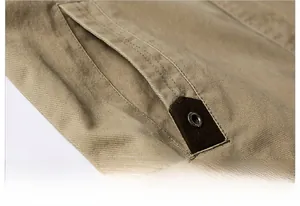 Detail shot of khaki outdoor jacket pocket with twill texture and reinforced metal rivets