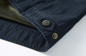 Détail macro d'une veste bleu marine avec bouton en laiton et surpiqûres blanches