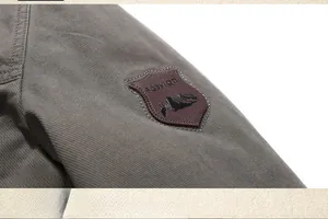 Dettaglio spalla giacca in cotone grigio-verde con toppa in pelle marrone moda