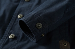 Gros plan de la veste outdoor bleu marine avec boutons en cuivre et coutures détaillées