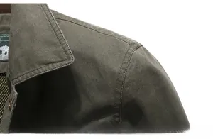 Macro detail of the military green outdoor jacket shoulder showing twill cotton texture