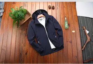 Detailed view of navy blue hooded windbreaker jacket with arm patch on wood background