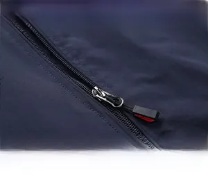Close-up of a premium silver metal zipper with red and black puller on blue jacket