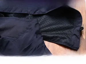 Detail of dark blue waterproof jacket hem showing black mesh lining and overlock seams