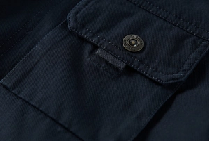 Macro shot of dark blue winter jacket pocket with fashion engraved metal button