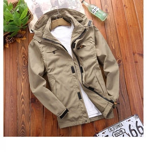 Flat lay of khaki hooded outdoor windbreaker with multiple pockets on wooden floor
