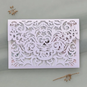 Detailed laser-cut lace invitation with floral inner card on elegant mesh backdrop