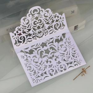 Detail of white laser cut invitation cover with elegant floral lace pattern for weddings