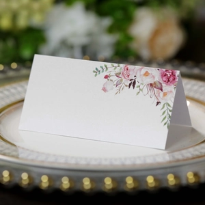 Dettaglio segnaposto bianco con rose rosa su un piatto di lusso con bordo dorato