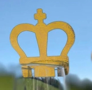 Golden crown place card with laser-cut hollow design placed on a transparent glass