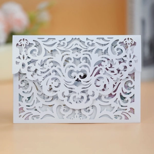 Close-up of white laser-cut wedding invitation featuring intricate scrollwork patterns