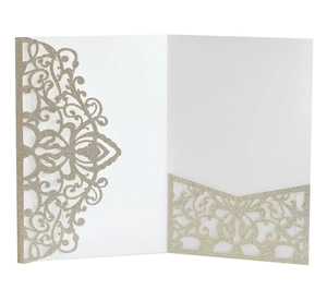 Macro detail of laser-cut wedding invitation with sparkling gold glitter and lace pattern