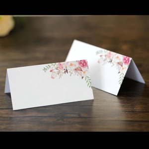 Eleganti segnaposti bianchi con rose rosa su tavolo in legno scuro per matrimoni