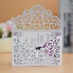 Macro detail of laser-cut floral pattern on elegant white wedding invitation with purple inlay
