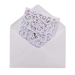 Macro shot of white laser cut wedding invitation set with intricate floral vine patterns