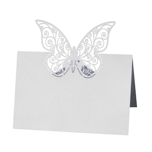Close-up of a white laser-cut butterfly place card featuring intricate hollow patterns