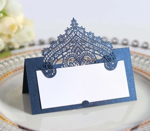 Detail showing blue glitter laser-cut lace crown place card on an elegant dinner plate
