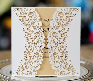 Laser cut white wedding invitation with floral patterns and kraft paper inner card