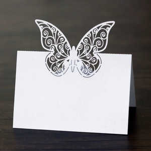 Close-up of laser-cut butterfly place card with intricate patterns on wood texture