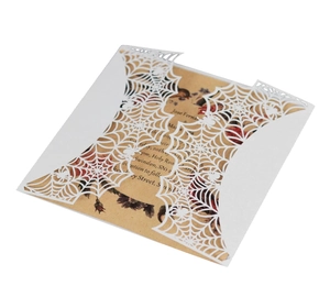 Intricate laser-cut white spider web invitation sleeve with rustic kraft inner card paper