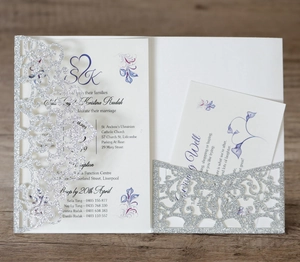 Close-up of laser-cut glitter wedding invitation with blue floral card on wood table