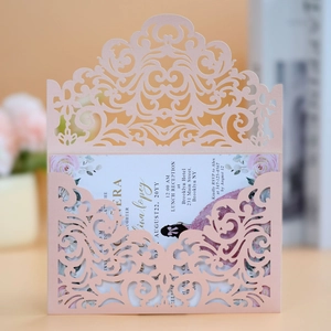 Detail of pink laser-cut wedding invitation with intricate floral hollow design and insert