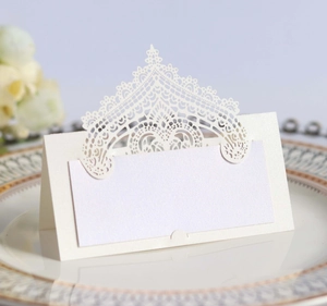 Detail of elegant pearl white laser-cut wedding place card with intricate lace pattern