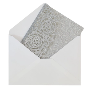 Detail of silver glitter invitation card with laser cut rose pattern and white envelope